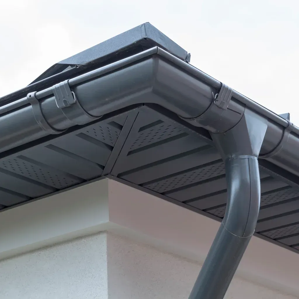 Gray roof gutter and downspout cloudy sky background Gray roof gutter and downspout, cloudy sky background