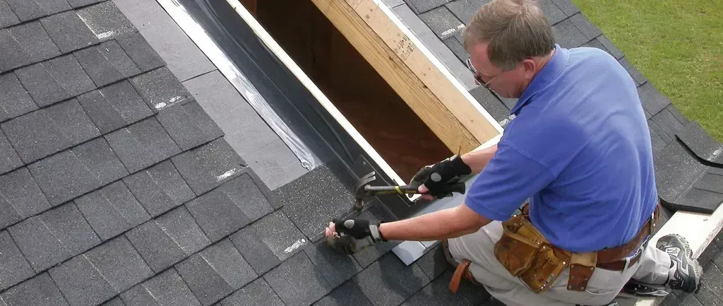 Man working on a roof installing shingles Man working on a roof, installing shingles