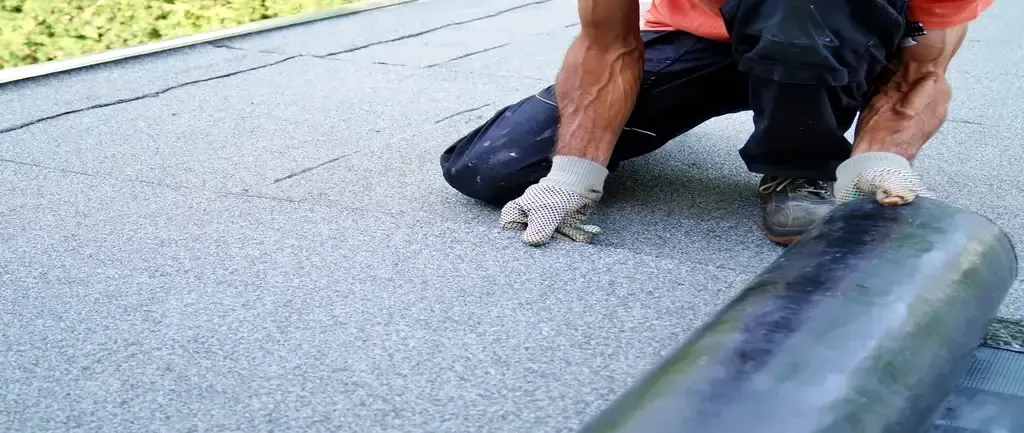 Person applying roofing material on a flat surface Person applying roofing material on a flat surface