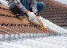 Person applying sealant on a roof with gloves Person applying sealant on a roof with gloves