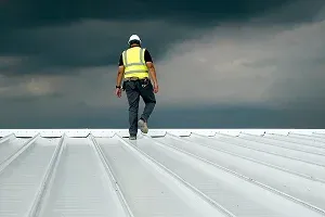 A construction worker walks on a metal roof