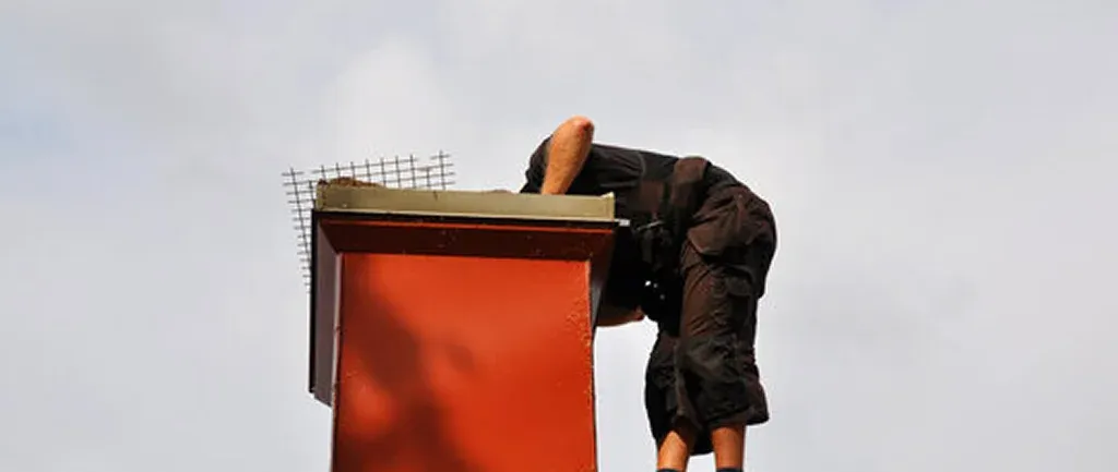 A technician bends over a red chimney A technician bends over a red chimney