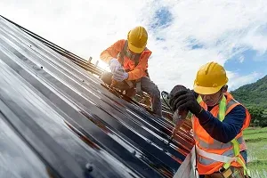 Two construction workers installing a metal roof
