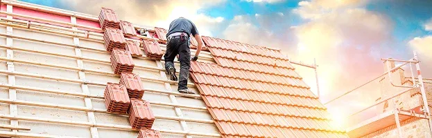Worker installing roof tiles on a building