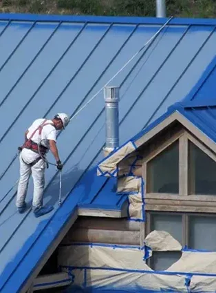 Worker painting a blue metal roof Worker painting a blue metal roof