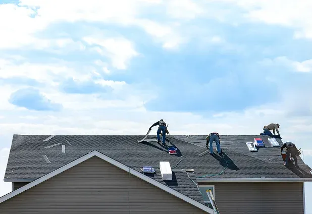 Workers installing roofing on a house under cloudy sky Workers installing roofing on a house under cloudy sky